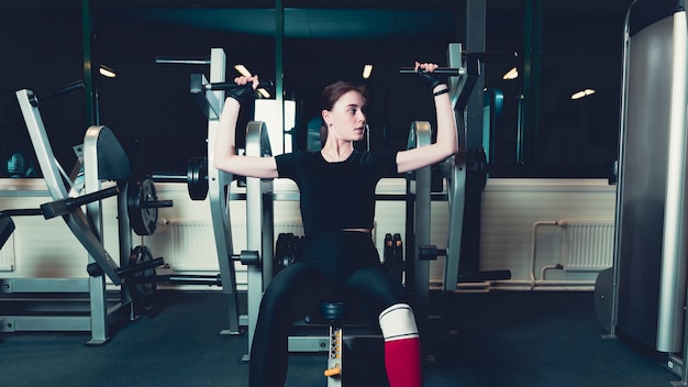 Young woman exercising on shoulder press machine