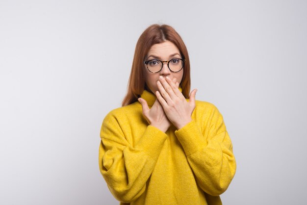 口を閉じる眼鏡の若い女性