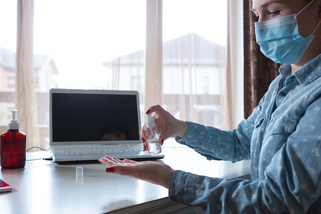 Foto gratuita la giovane donna nella maschera di disinfezione disinfetta le superfici sul suo posto di lavoro