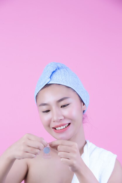 Young woman face mask pad pink background.