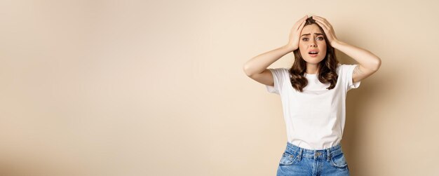 Young woman facing disaster looking anxious in panic holding hands on head frustrated standing over