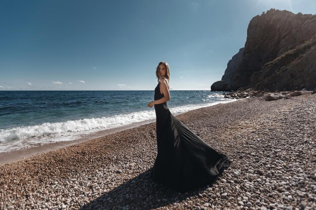 ビーチでファッションの黒いドレスを着た若い女性