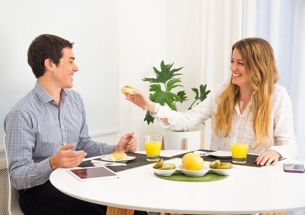 Young woman feeding bread to her husband at breakfast