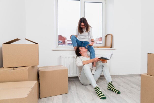 Young woman feeding pizza slice to her boyfriend in their new home