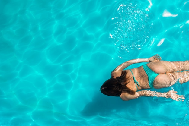 スイミングプールに浮かぶ若い女性