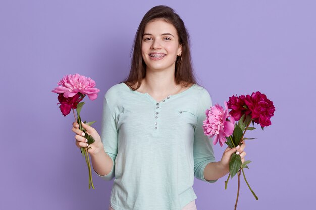 Флорист молодая женщина делает букет с цветами, держа в руках пионы