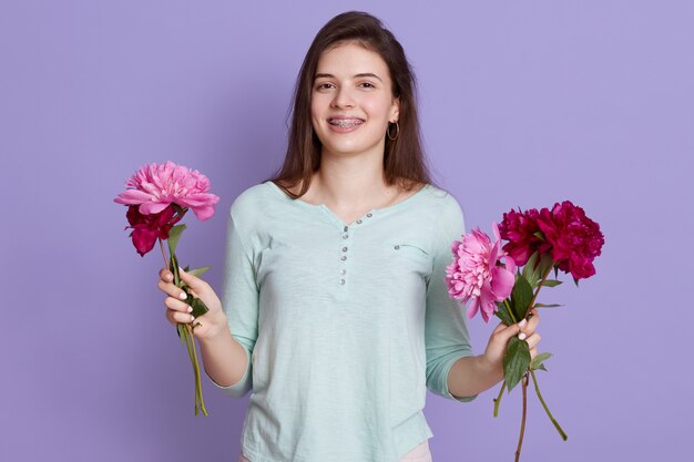 young woman florist making bouquet with flowers, holding peonies in hands