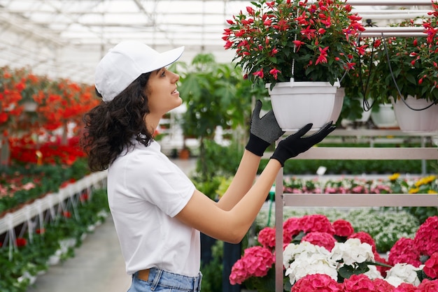 Young woman florist taking care for plants in greenhouse
