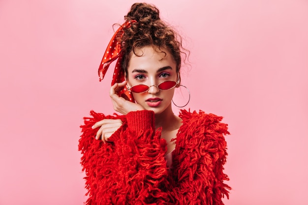 Young woman in fluffy jacket and red sunglasses looking into camera