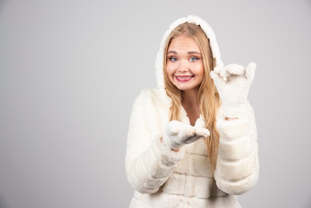 Young woman in fur coat showing something on open space.