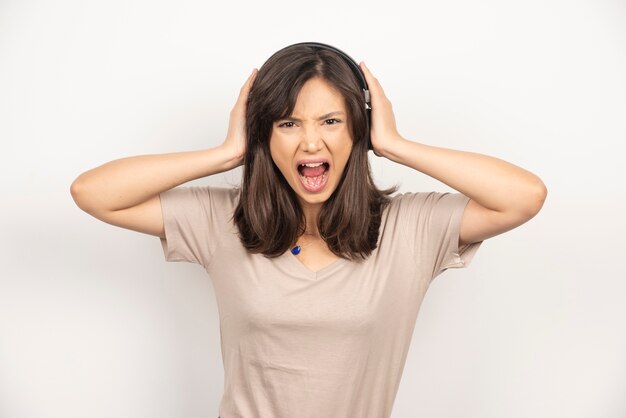 Young woman getting angry on white background.