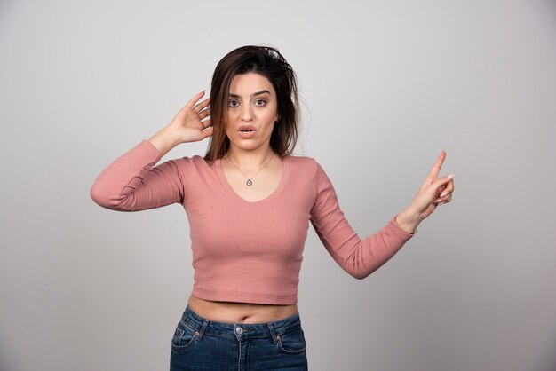 Young woman girl in casual clothes posing and pointing away. 