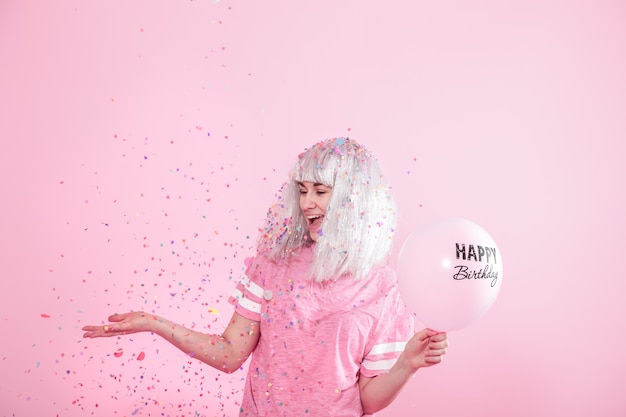 Young woman or girl with balloons happy Birthday. Throws confetti from above. Holiday and party concept.