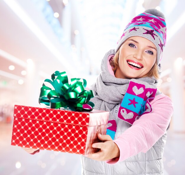 young woman gives the christmas gift dressed in a winter outerwear