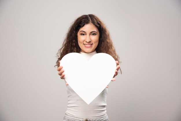 young woman giving a white handmade paper heart. high quality photo