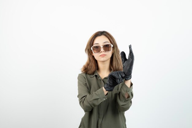 Young woman in glasses trying on black gloves over white. High quality photo