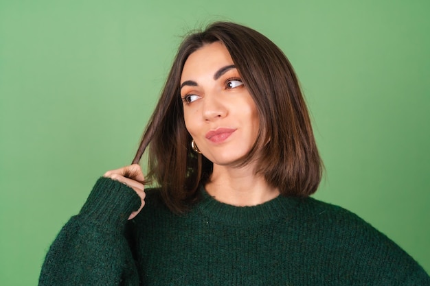 Giovane donna sul verde in un accogliente maglione lavorato a maglia carino sorridente