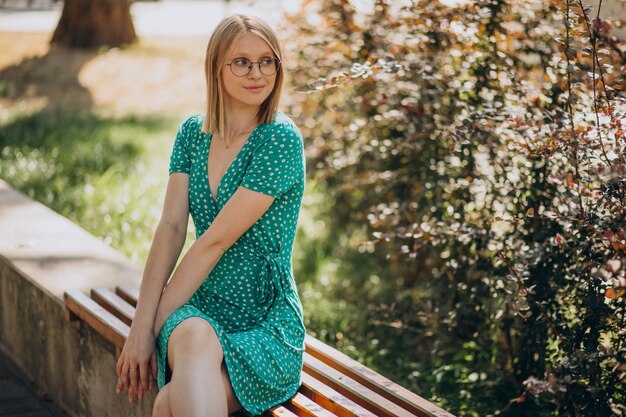 公園に座っている緑のドレスの若い女性