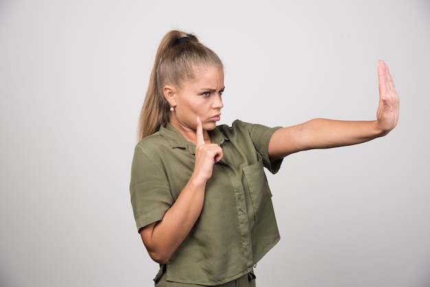 Young woman in green jacket offering her hand to reject.