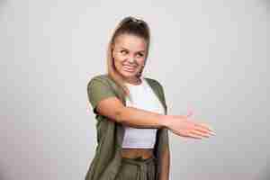 Free photo young woman in green jacket offering her hand to shake.