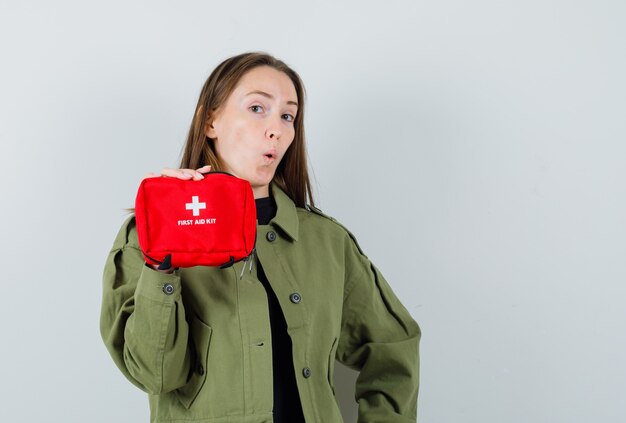 Free Photo young woman in green jacket showing first aid kit , front view.
