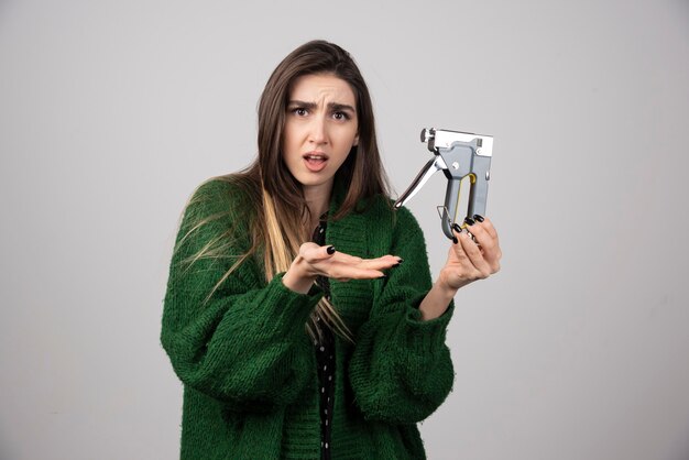 Young woman in green jacket showing a working tool.