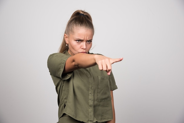 Young woman in green outfit pointing something.