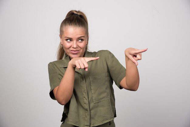 Young woman in green outfit pointing something.