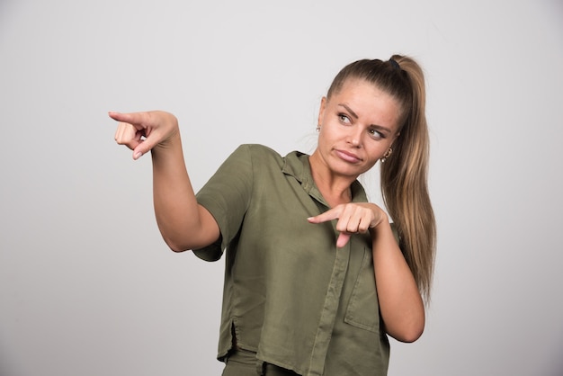 Foto gratuita giovane donna in abito verde che indica qualcosa.