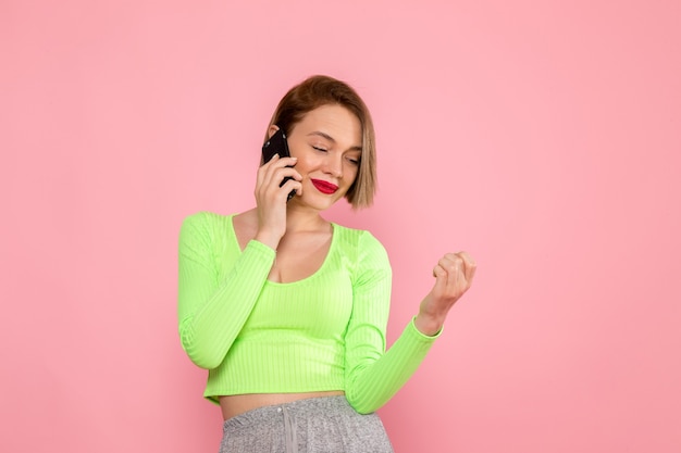 young woman in green shirt and grey skirt talking on the phone