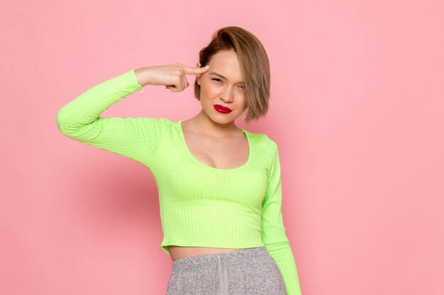 young woman in green shirt and grey skirt touching her head with angry expression