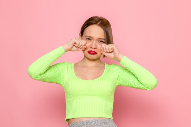 Foto gratuita giovane donna in camicia verde e pantaloni grigi finta di piangere