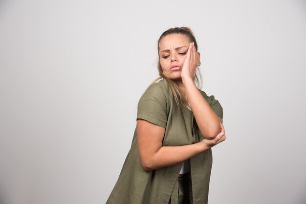 Young woman in green shirt having toothache.