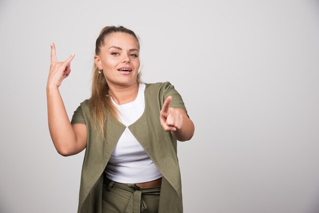 Young woman in green shirt pointing at camera.