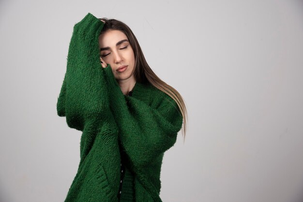 Young woman in green sweater sleeping on gray.