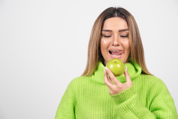 Foto gratuita giovane donna in maglietta verde che mangia una mela.