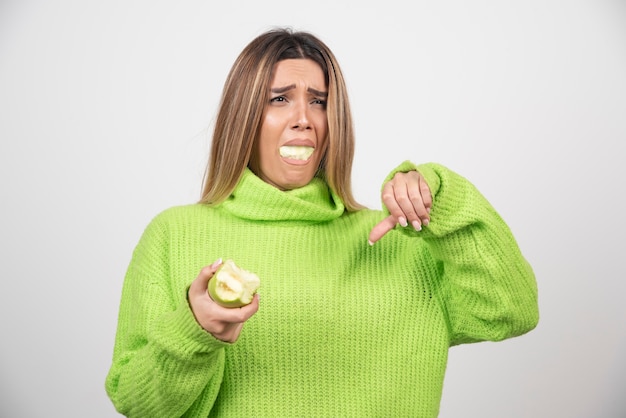 リンゴを食べる緑のTシャツの若い女性。