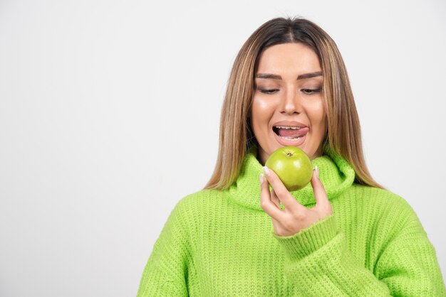 リンゴを食べる緑のTシャツの若い女性