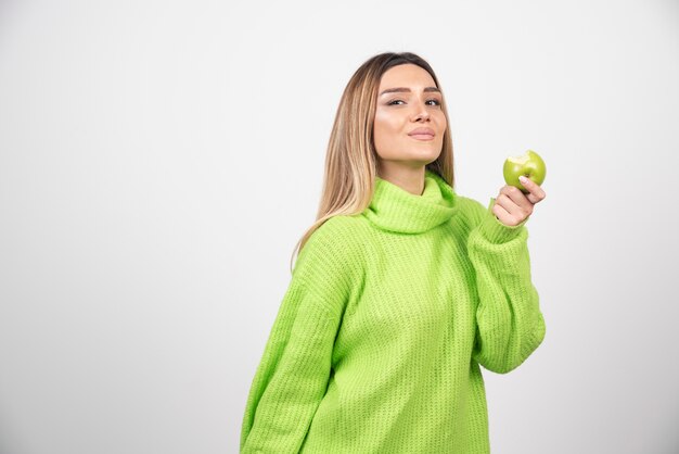 사과 들고 녹색 티셔츠에 젊은 여자.