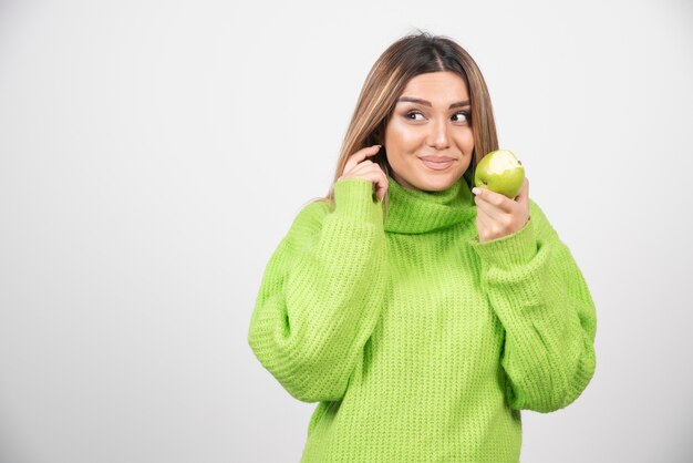 Young woman in green t-shirt holding an apple