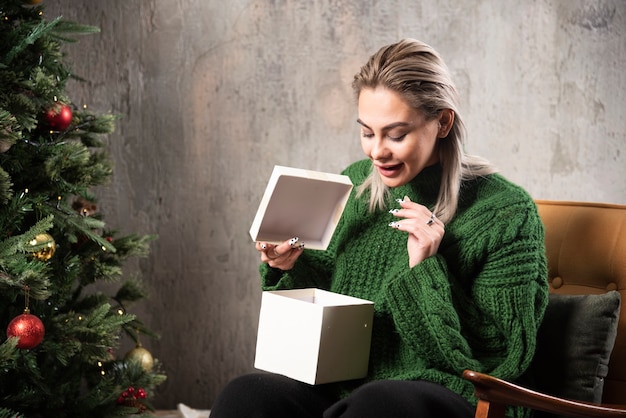 녹색 따뜻한 스웨터에 젊은 여자는 선물에 대 한 흥분