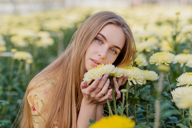 花が付いている温室の若い女性