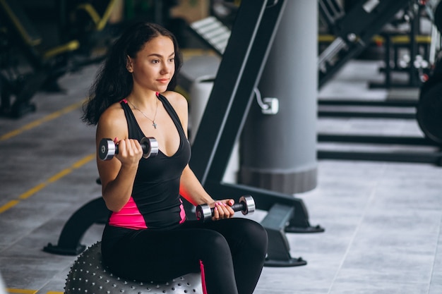 Foto gratuita giovane donna in palestra che si esercita con attrezzatura