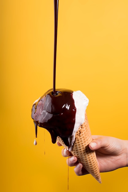 Young woman hand holding melting ice cream - chocolate splash