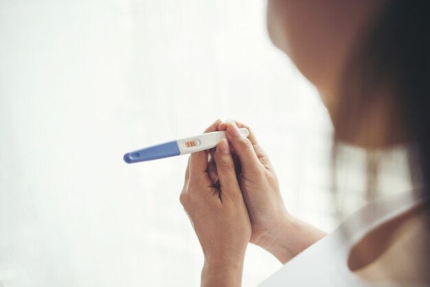 妊娠テストを握る若い女性の手