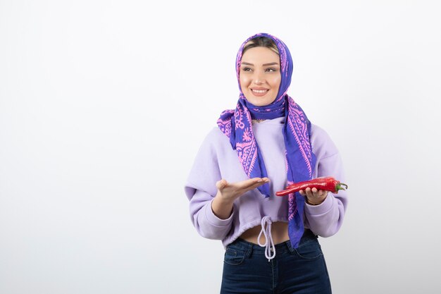 young woman in handkerchief holding a red pepper.