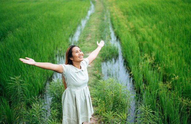 晴れた日に緑の野原で喜んで若い女性