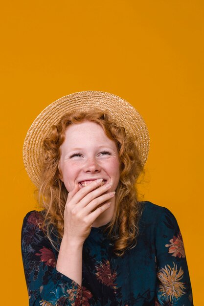 Young woman in hat laughing and covering mouth