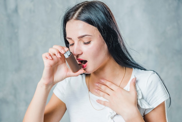 健康であるために喘息吸入器を使用する喘息アレルギーを有する若い女性