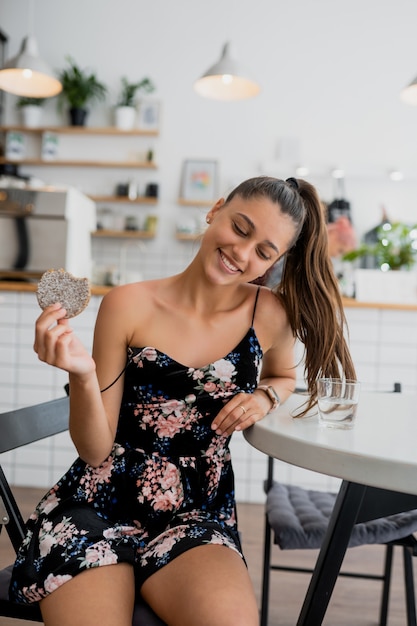 Young woman having breakfast in a cozy cafe. Happy smiling girl holds cookie.